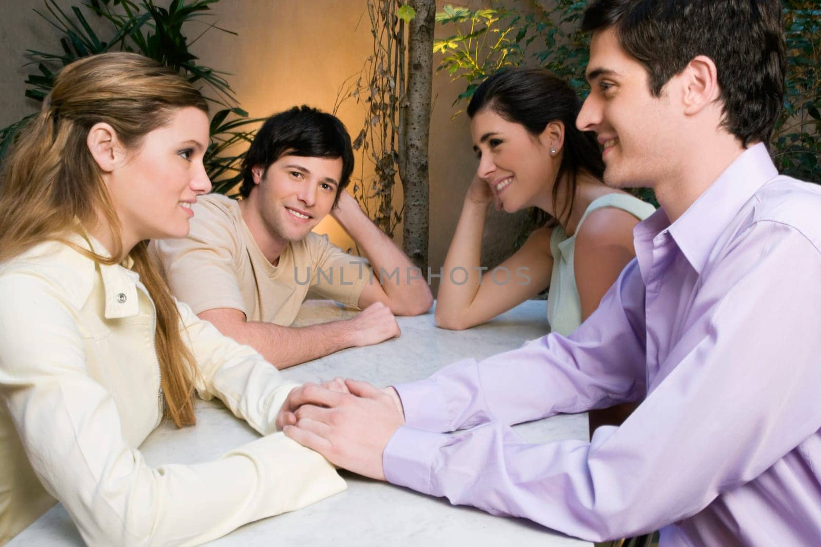 Two young couples sitting in a cafe and smiling