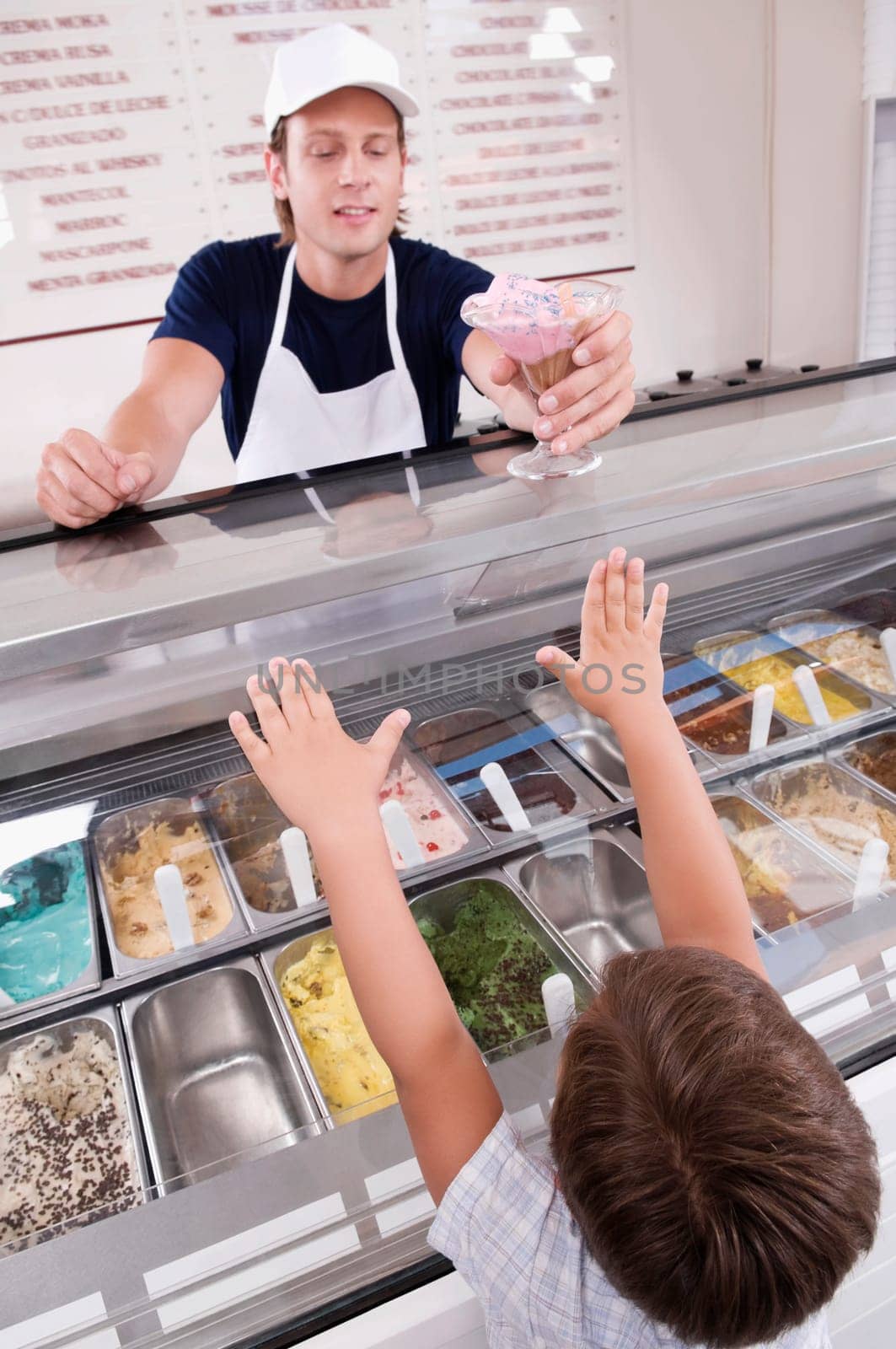 Sales clerk giving ice cream to a boy in an ice cream parlor