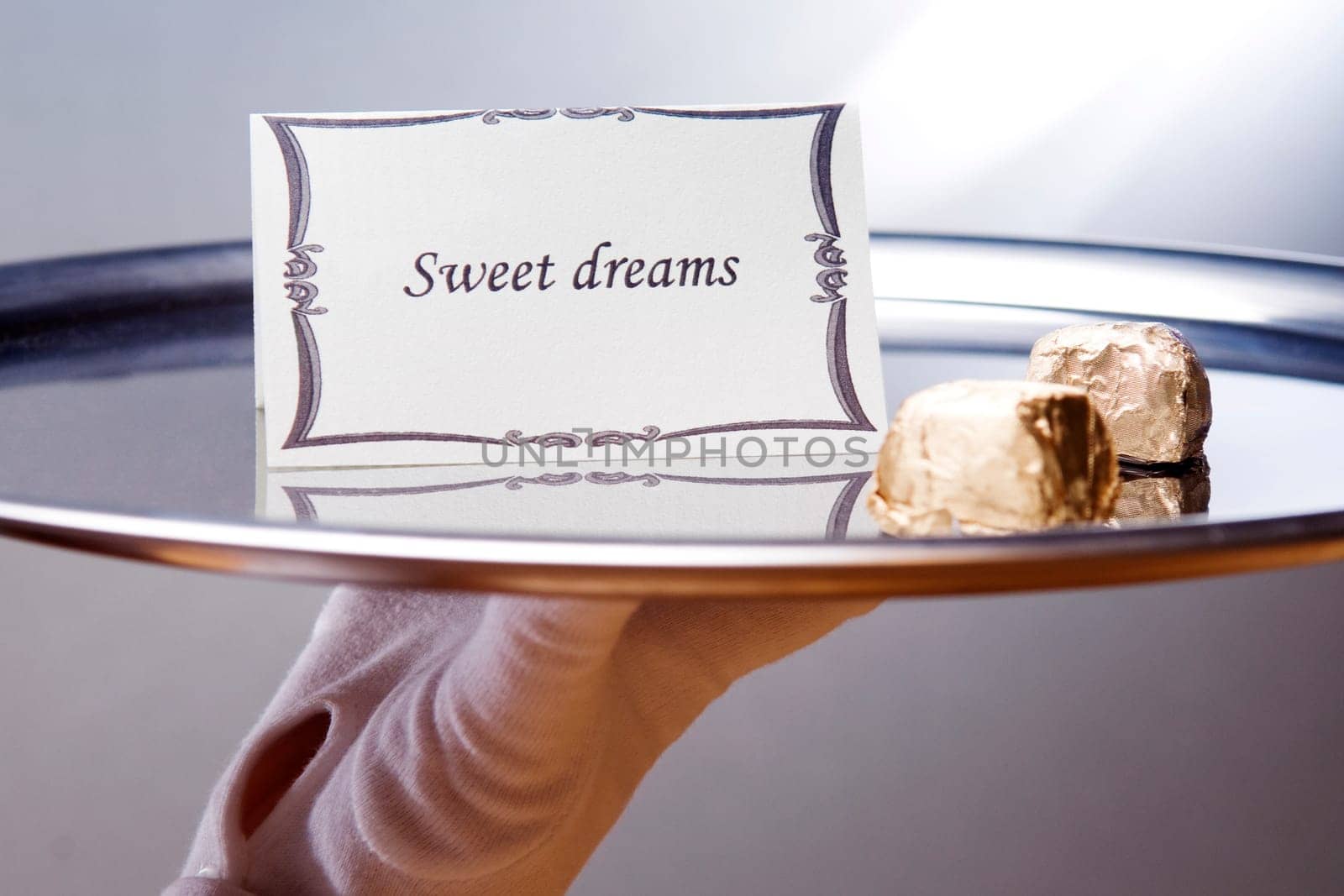 Close_up of a waiterŽs hand carrying a plate with sweet dreams note and chocolates