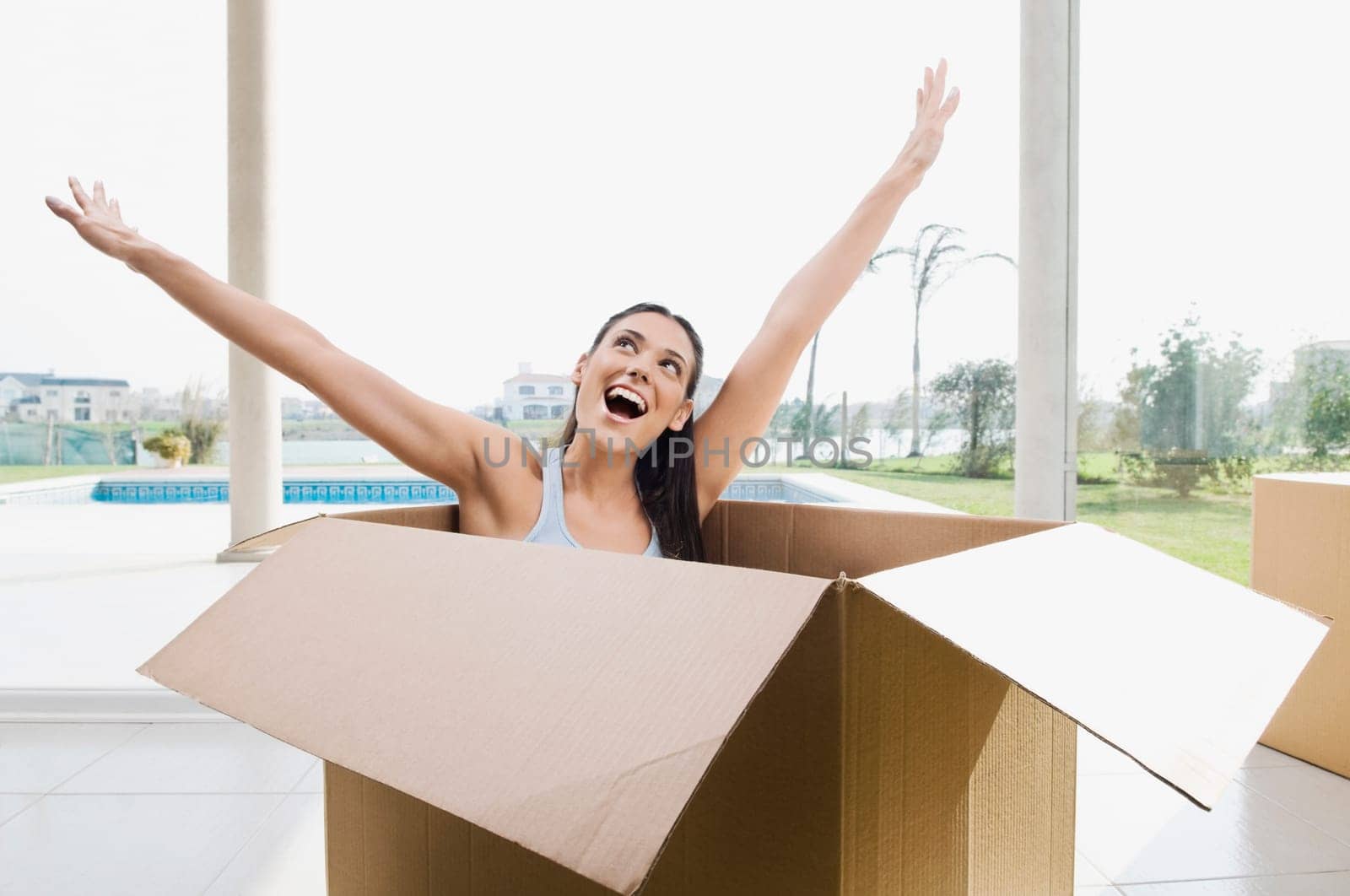 Young woman sitting in a cardboard box and laughing