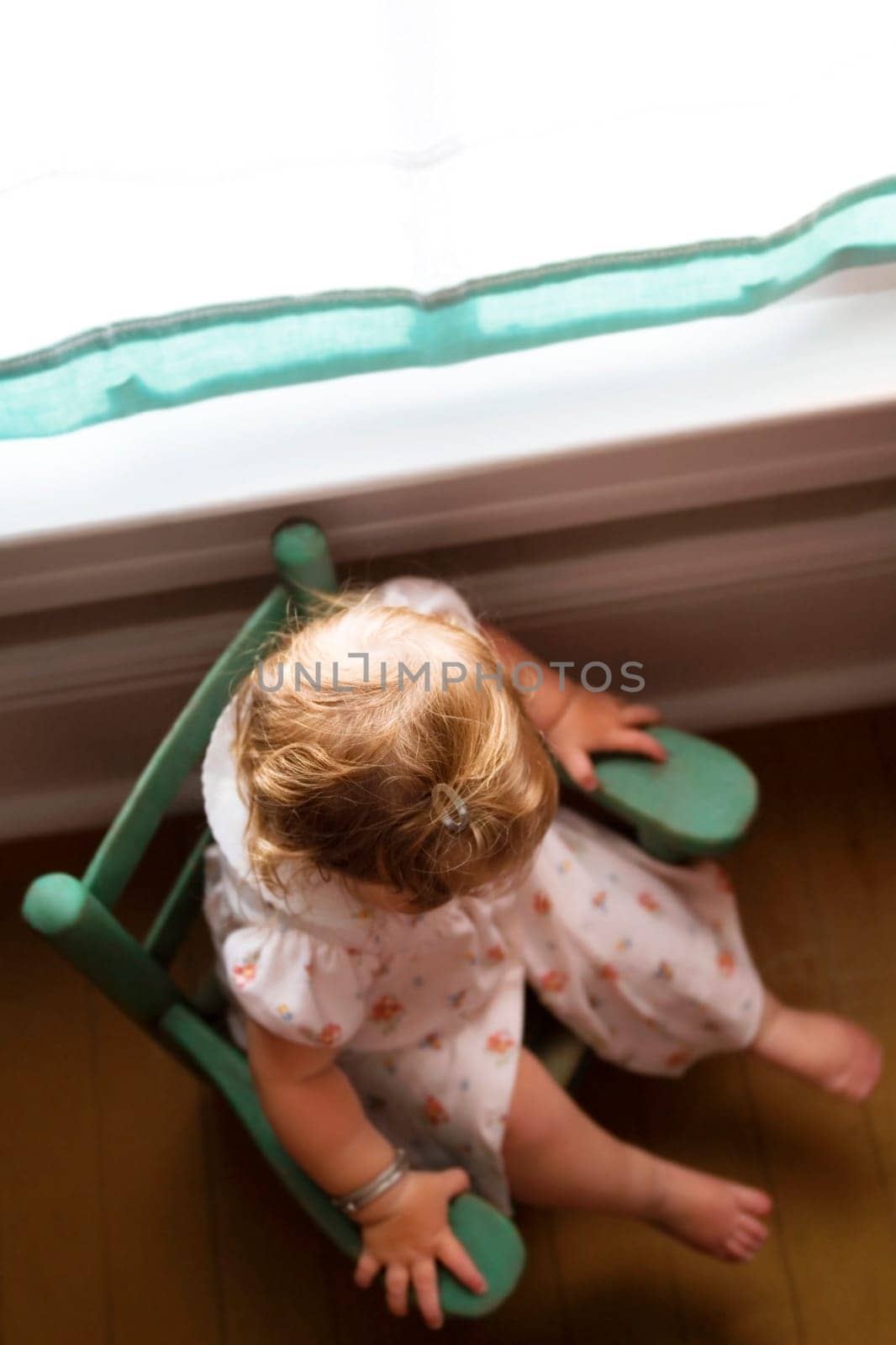 High angle view of a baby girl sitting in an armchair