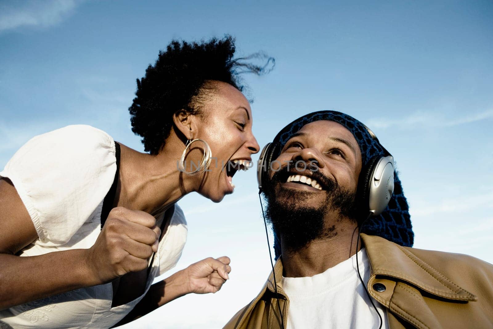 Mid adult man listening to music and a young woman shouting in front of him
