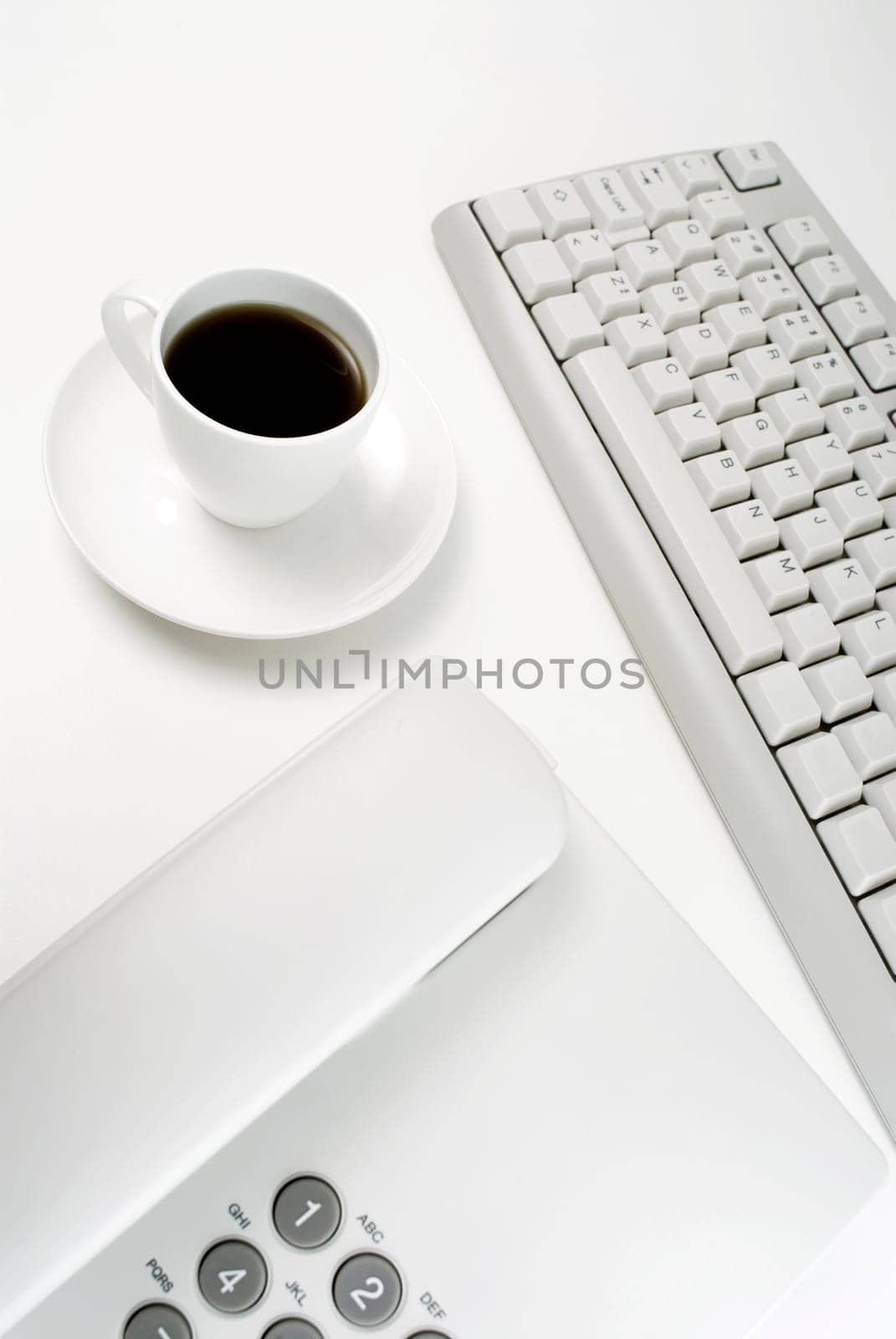 Close_up of a telephone and a computer keyboard with a cup of tea