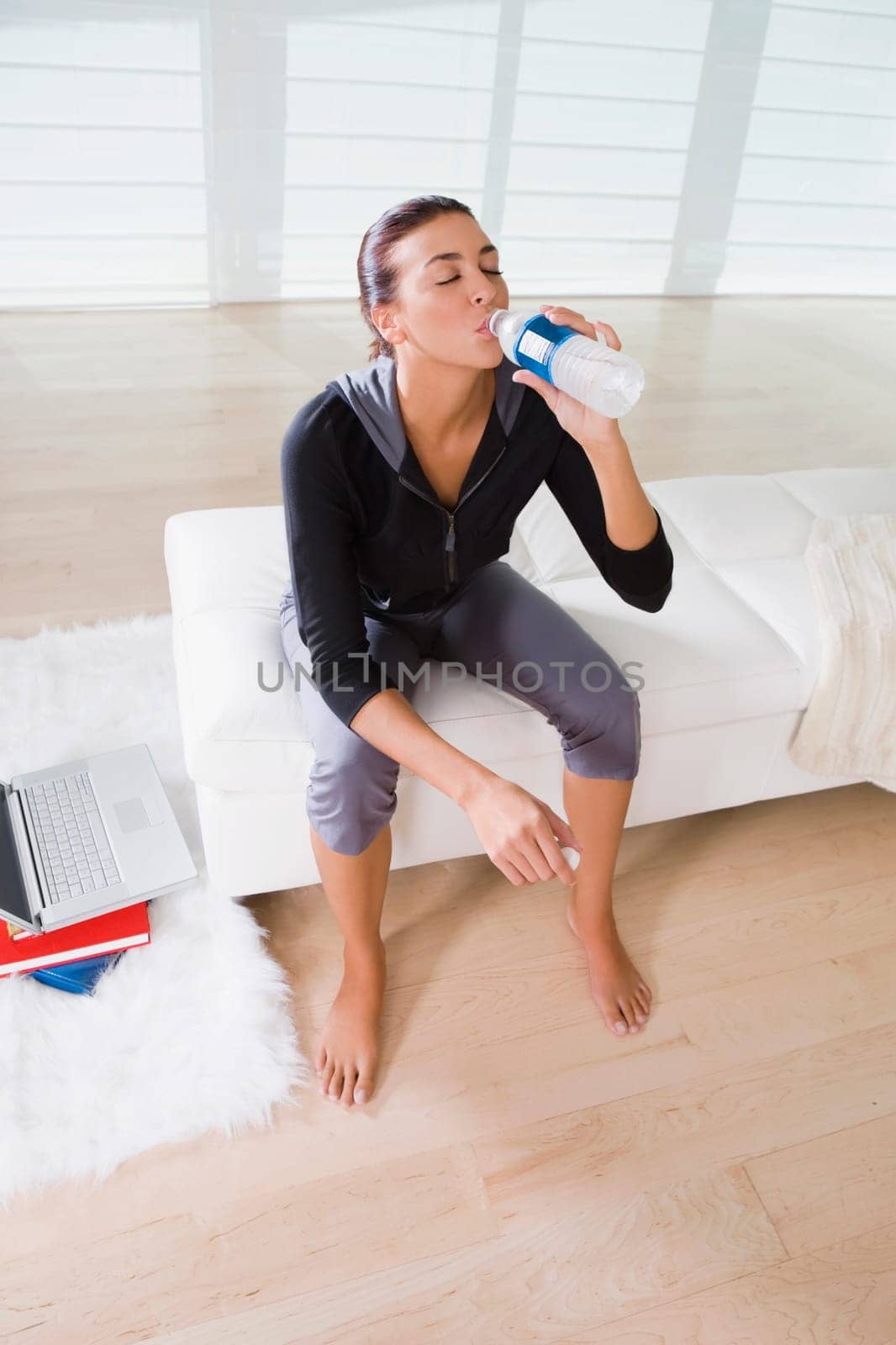 Young woman sitting on the bed and drinking water