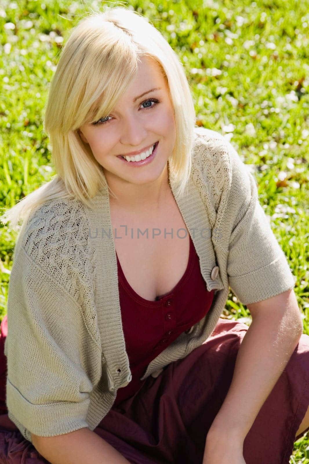 Portrait of a young woman crouching in a park and smiling
