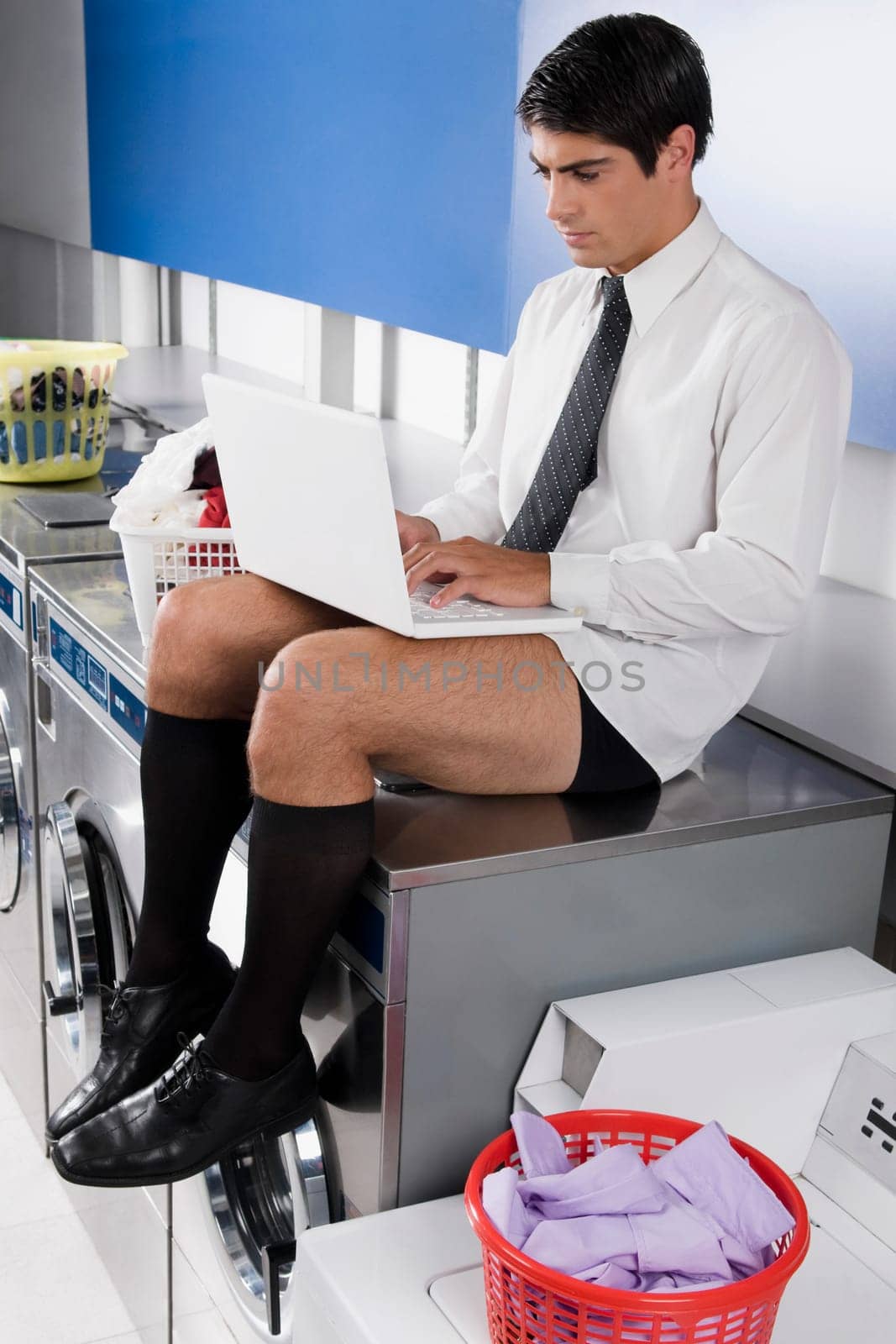 Businessman working on a laptop in a laundromat