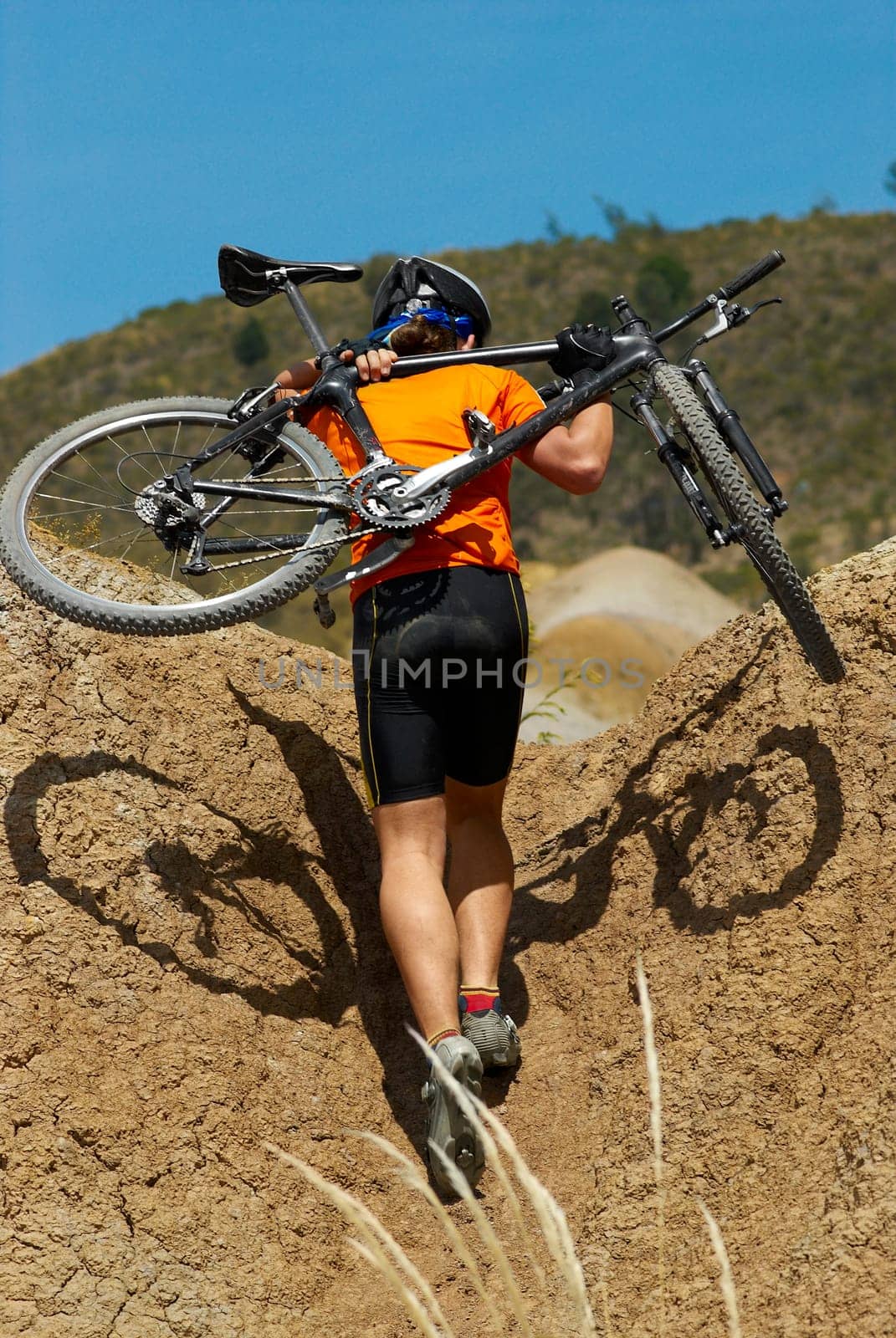 Rear view of a man carrying a mountain bike on his shoulders