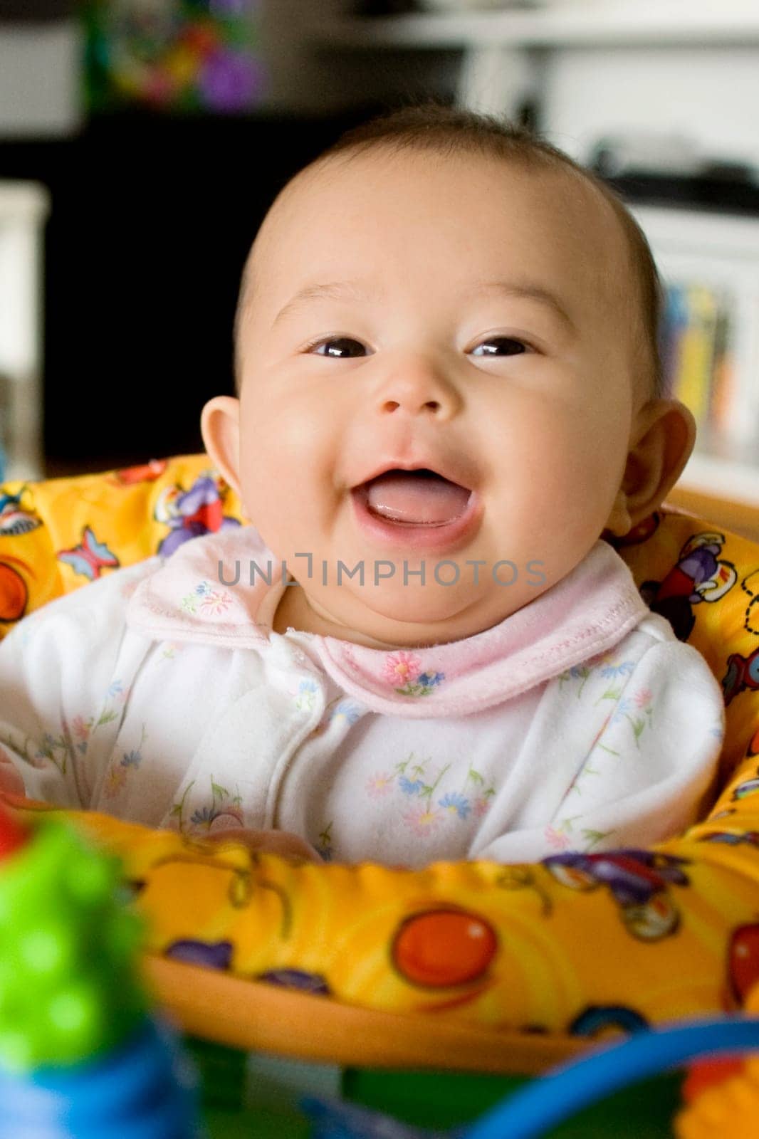 Portrait of a baby girl sitting in a toy swing and smiling
