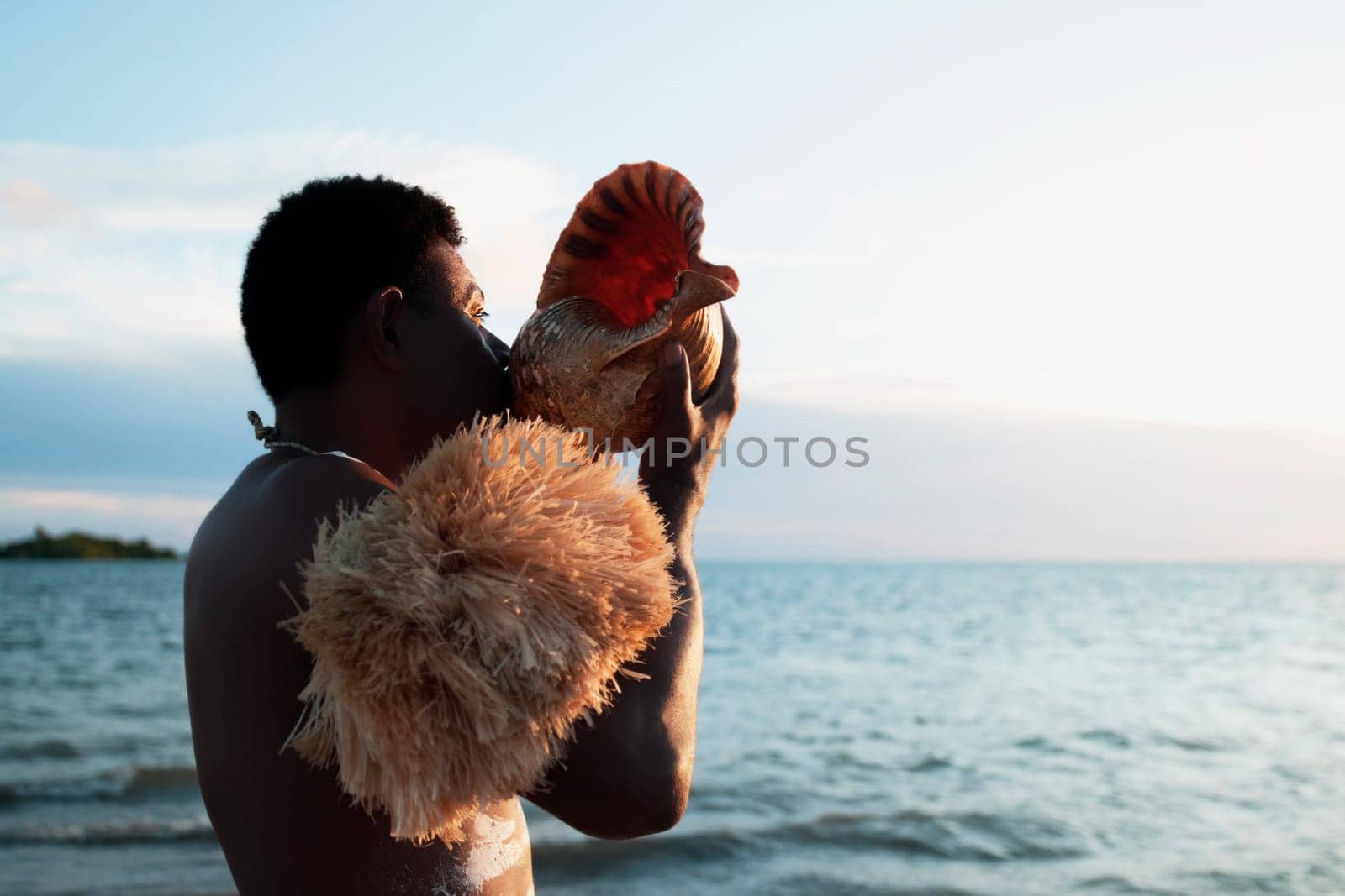 Tribesman blowing a cockleshell on the beach