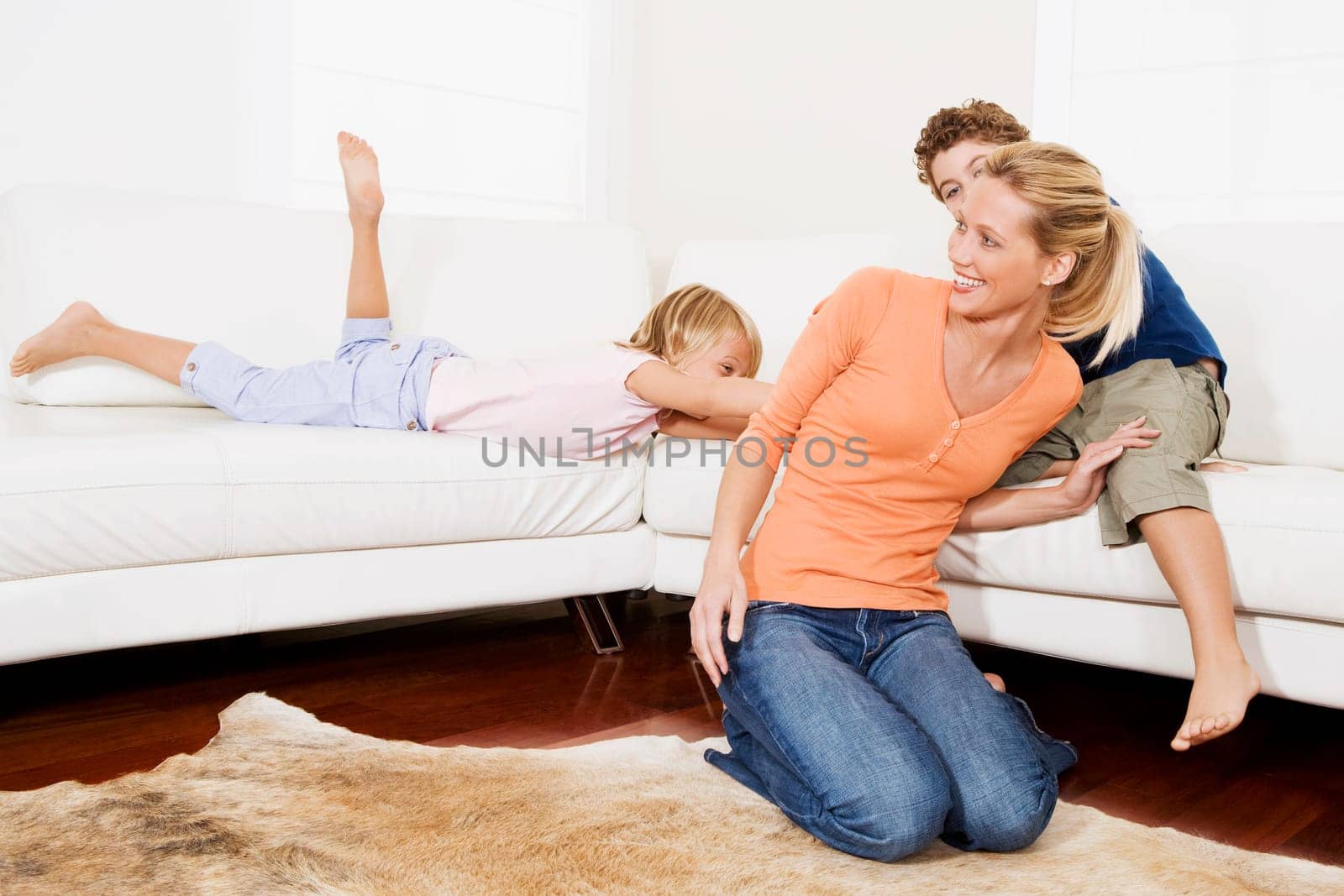 Woman playing with her son and a daughter in a living room