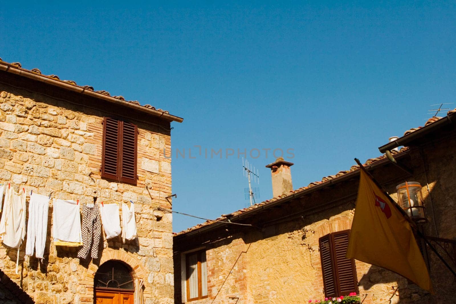 Low angle view of clothes drying in front of a house, San Gimignano, Siena Province, Tuscany, Italy