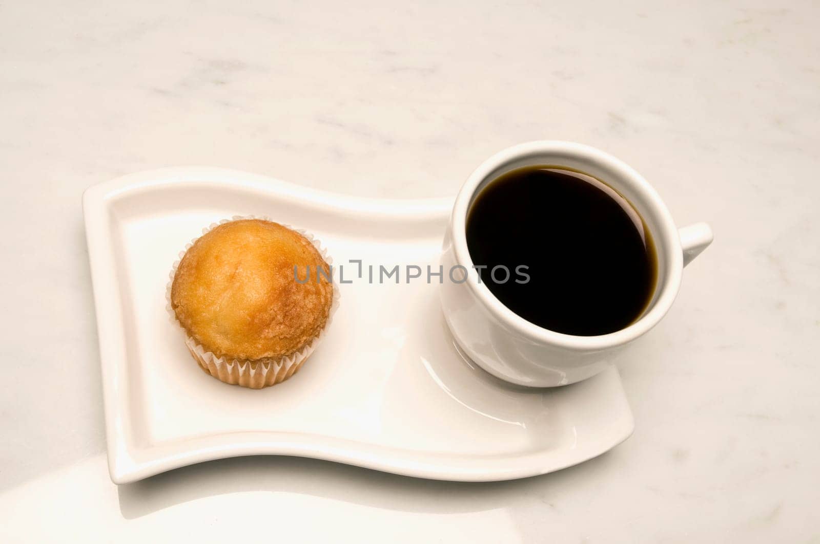 Close_up of a cup of black coffee and a cupcake in a serving tray