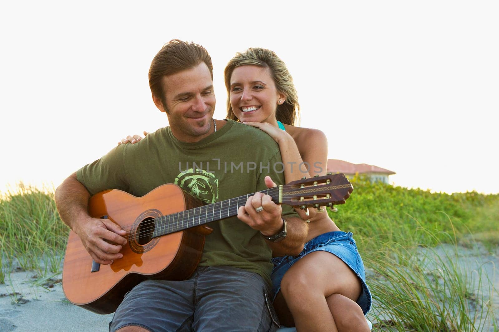 Mid adult man playing a guitar with a young woman smiling