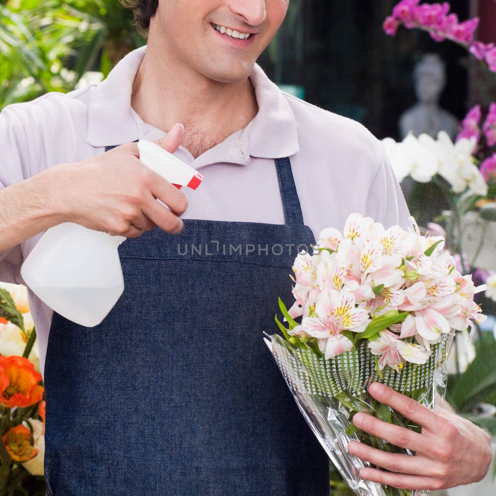 Florist spraying water on a bouquet of flowers