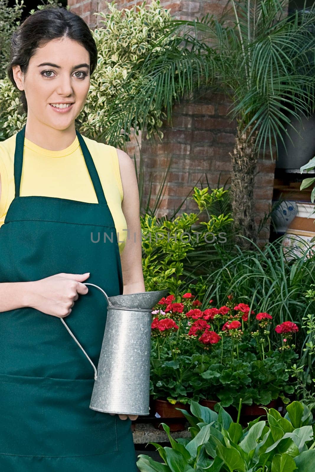Woman holding a watering can in a greenhouse