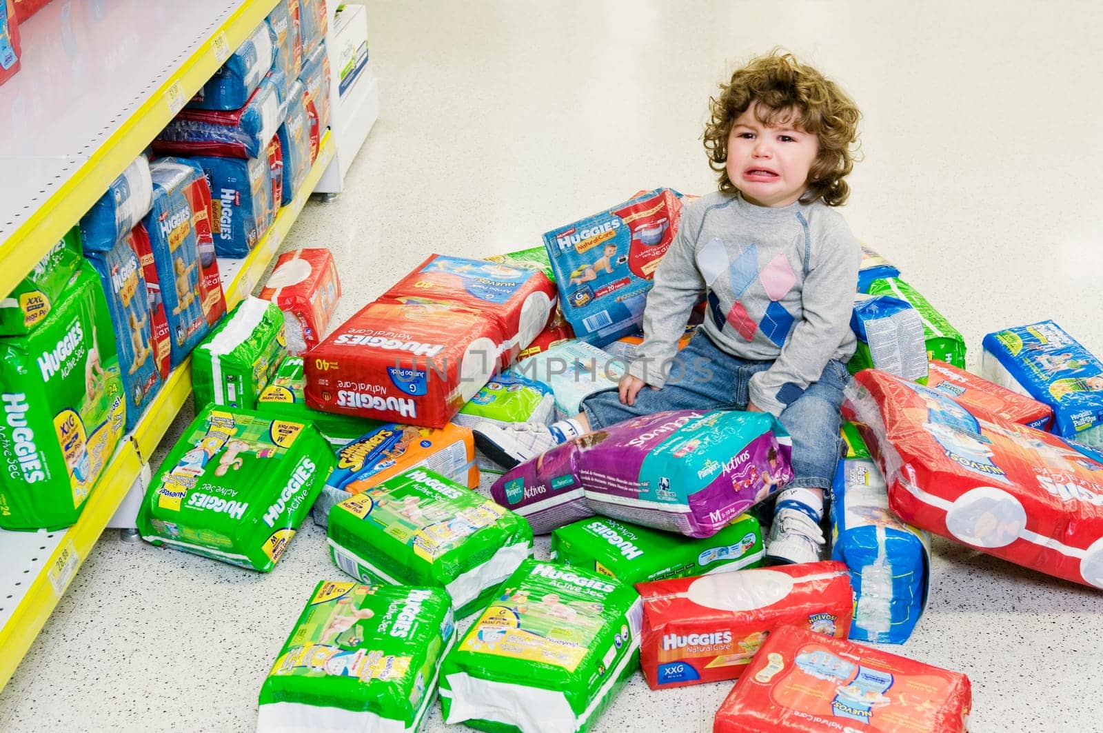 Baby boy crying with a heap of diapers around him