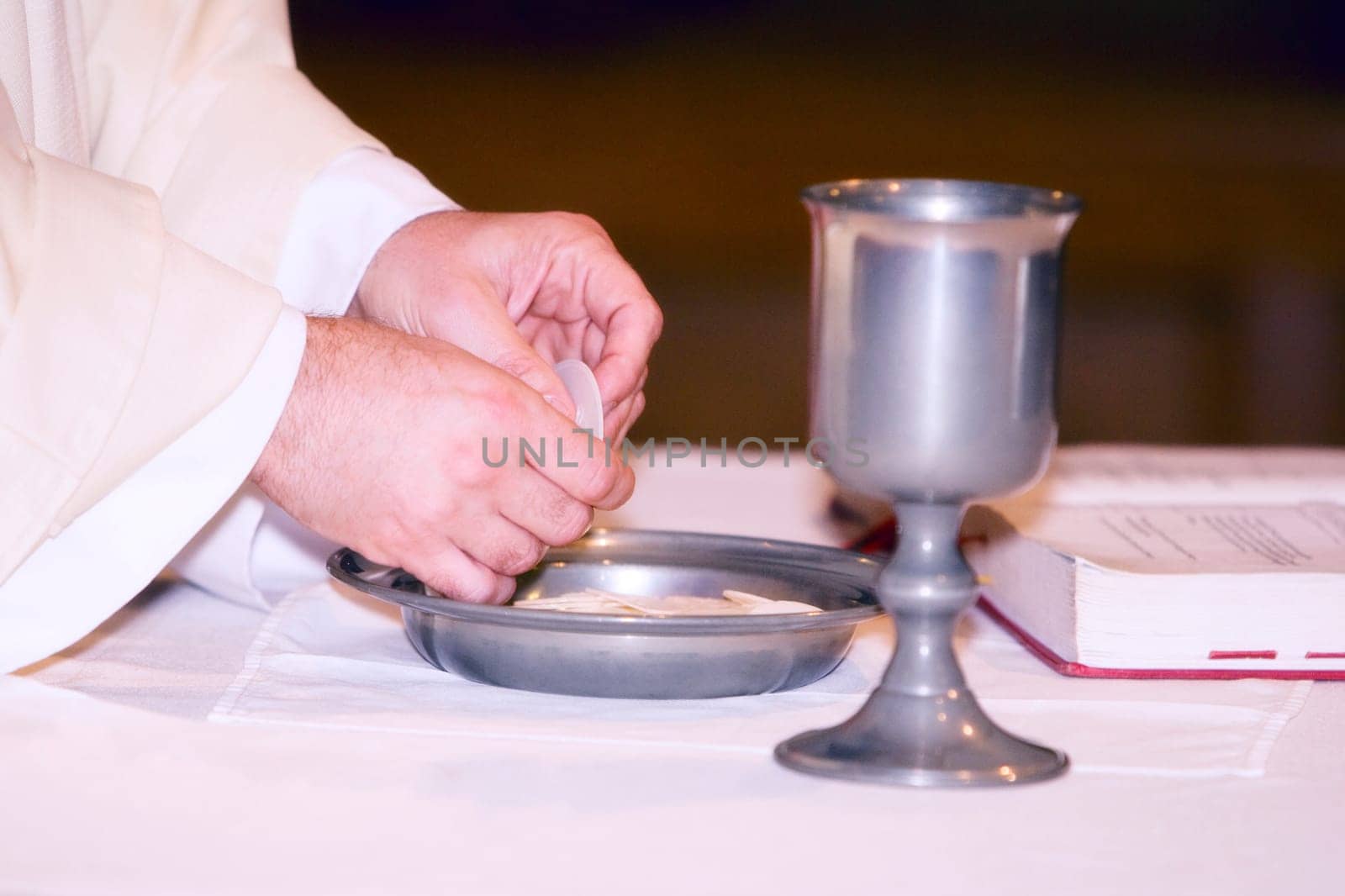 Close_up of hands of a priest breaking bread