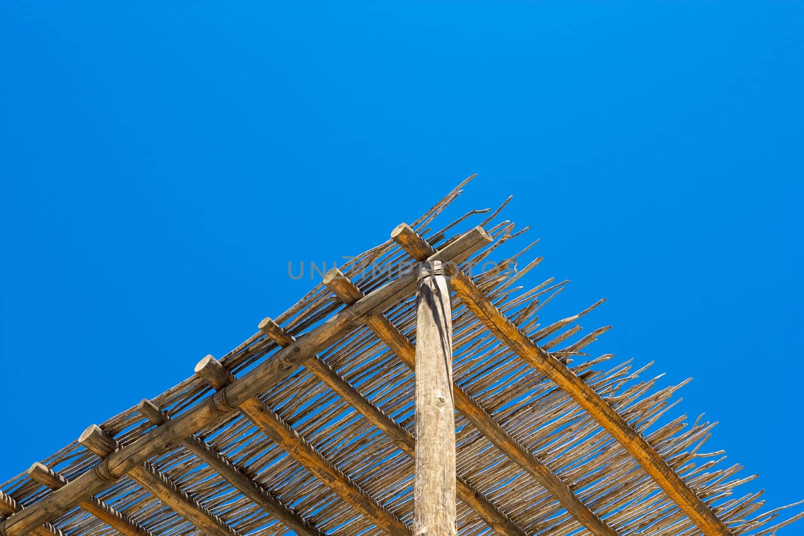 Low angle view of a thatched roof against the blue sky