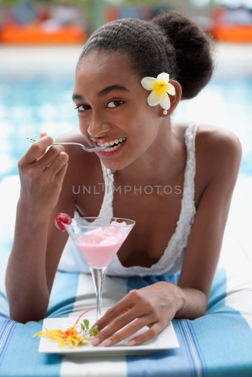 Portrait of a woman lying at the poolside and eating ice cream