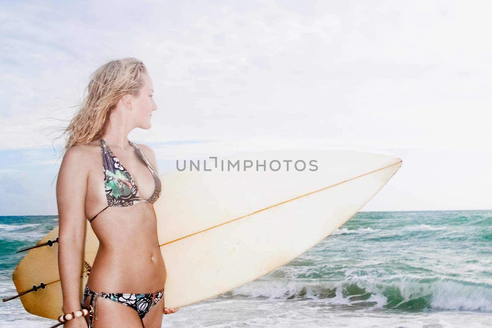 Young woman with a surfboard standing on the beach