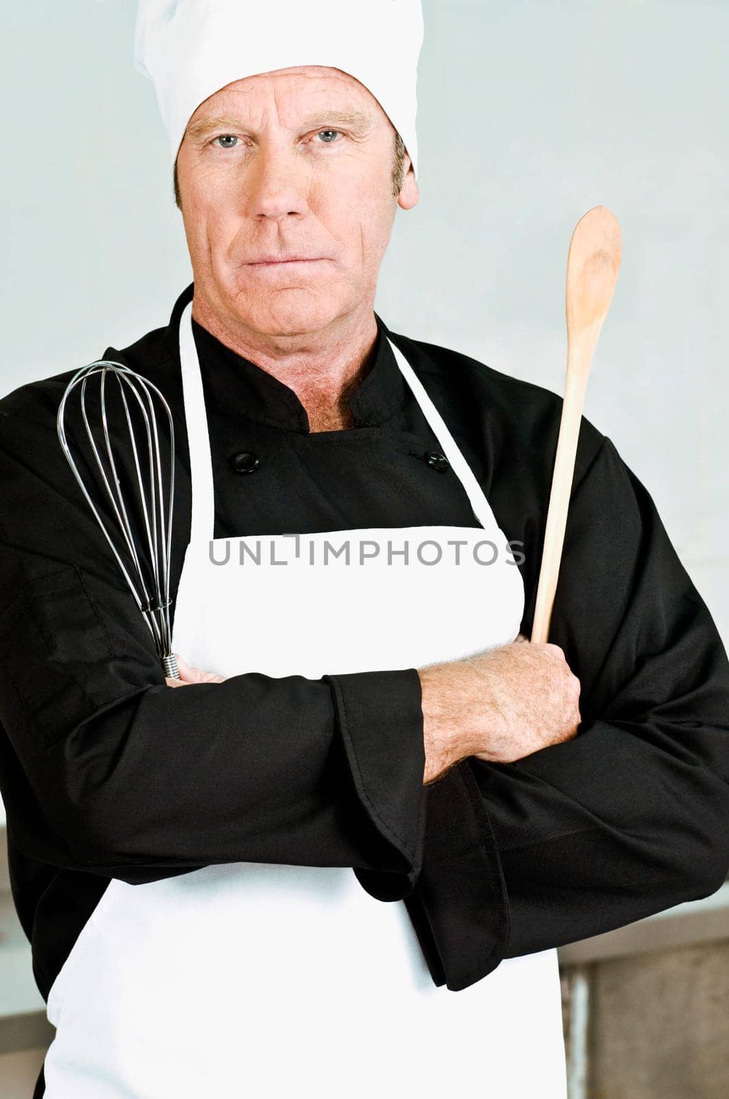 Chef holding a wooden spoon and a wire whisk