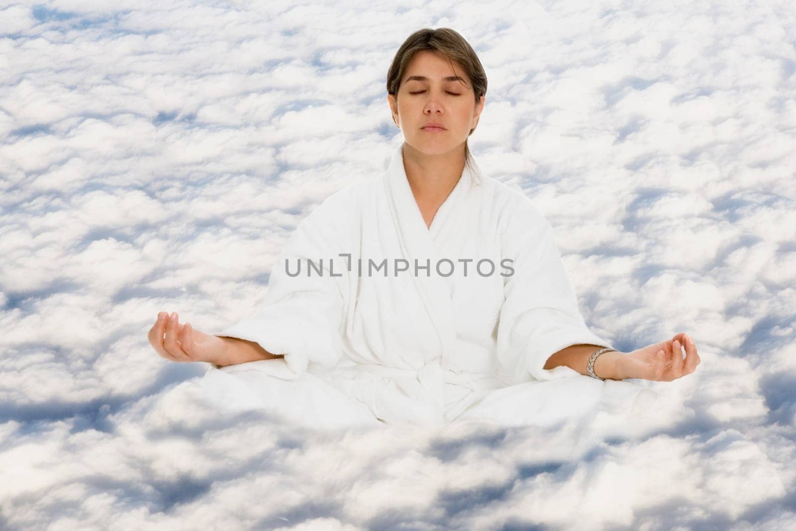 Mid adult woman practicing yoga on clouds