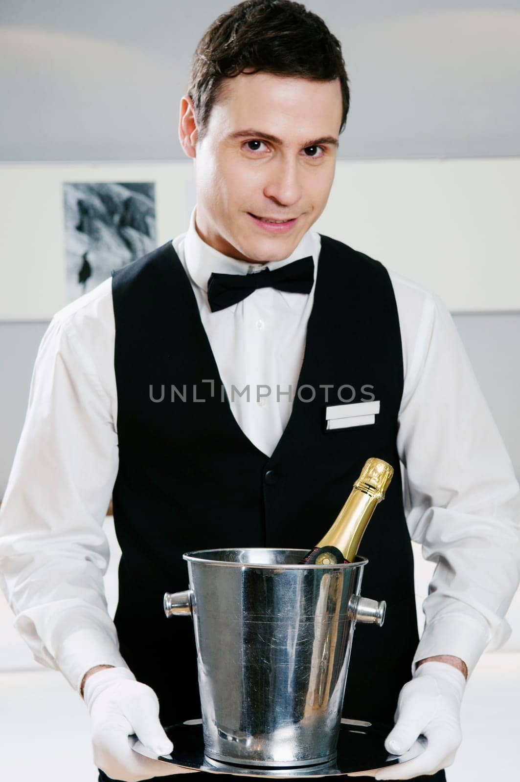 Portrait of a waiter holding a champagne bottle in an ice bucket