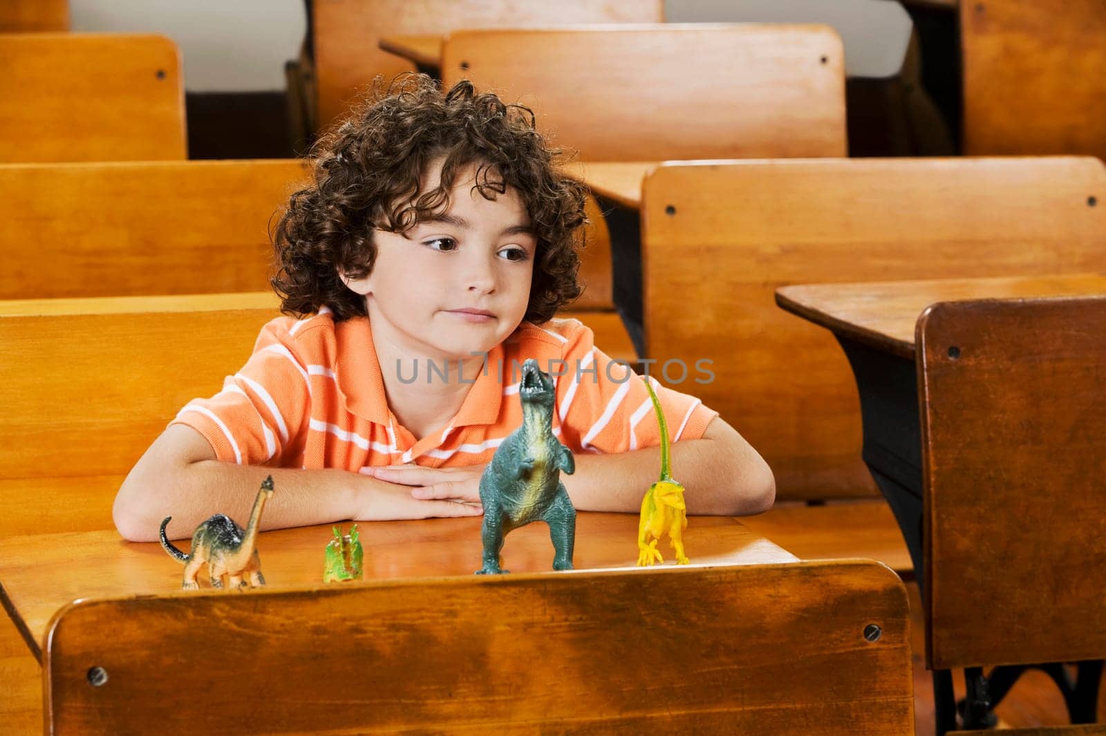 Schoolboy sitting with toys in a classroom