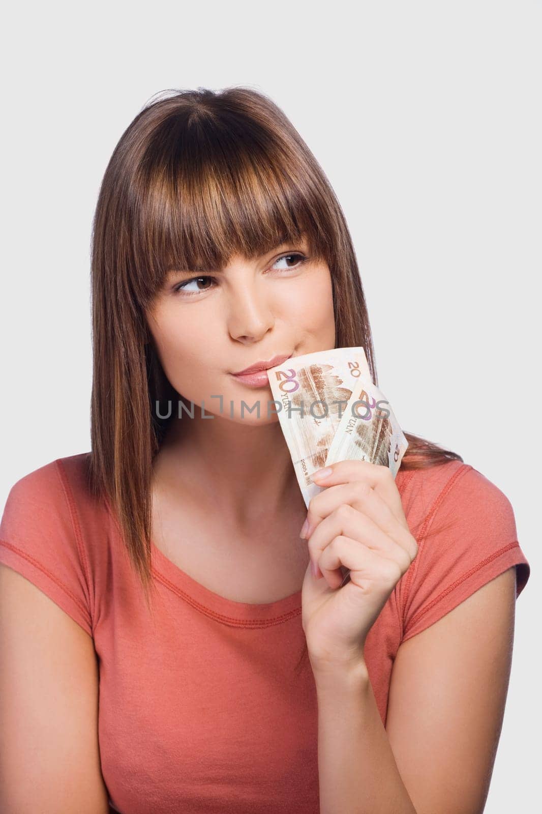 Close_up of a young woman holding Euro banknotes and thinking