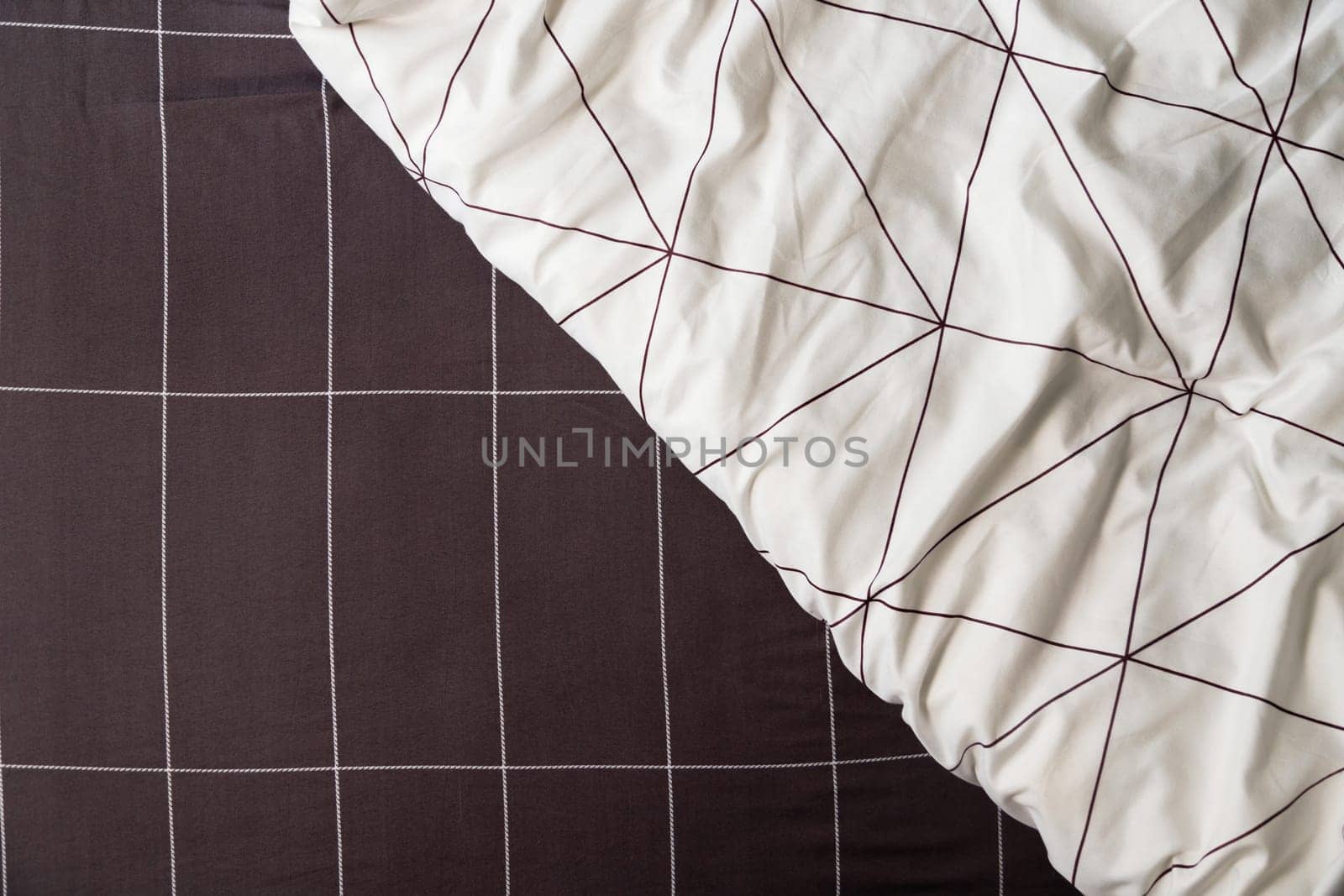 Elegant linen plaid sheet and white blanket with geometric design.