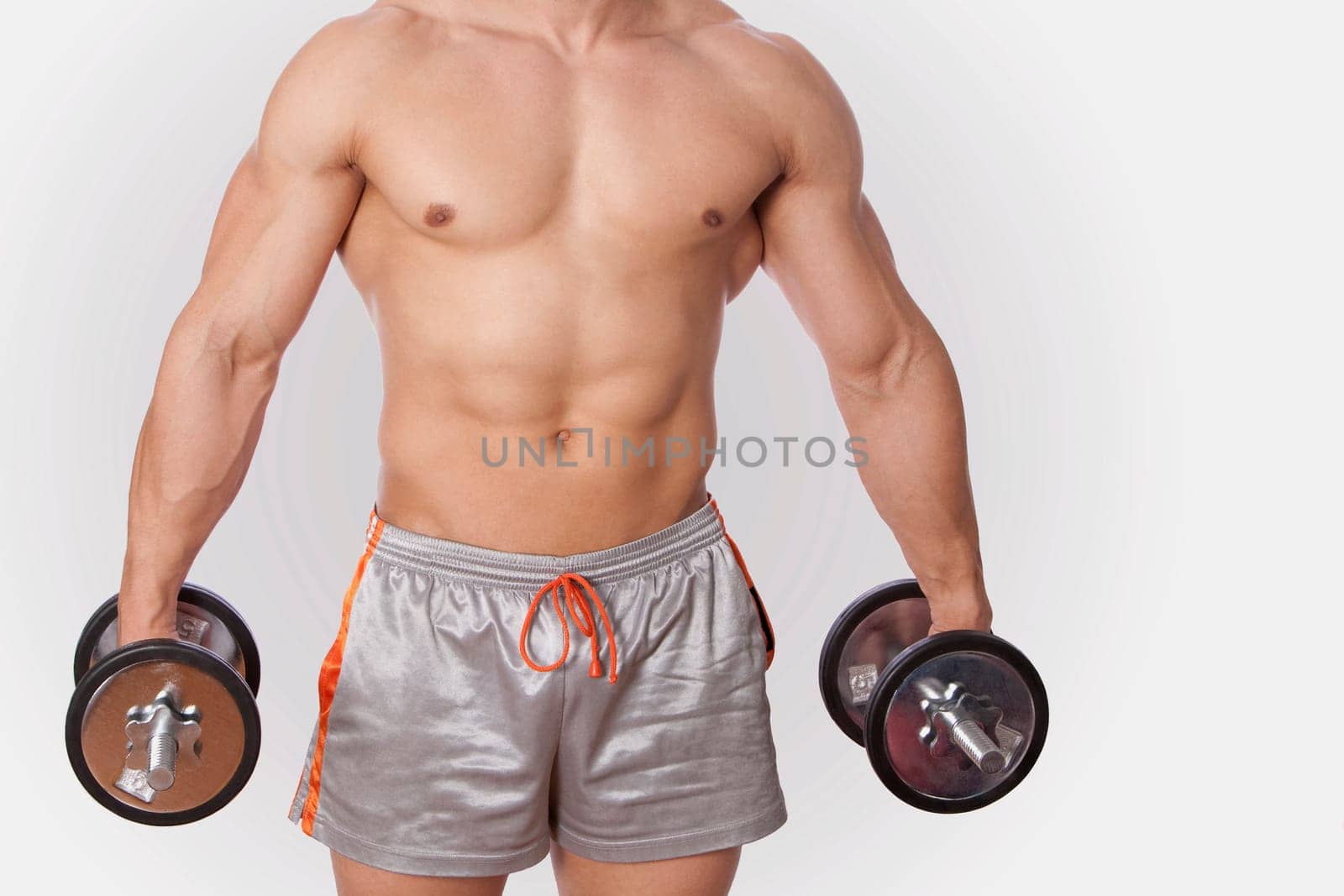 Mid section view of a man exercising with dumbbells