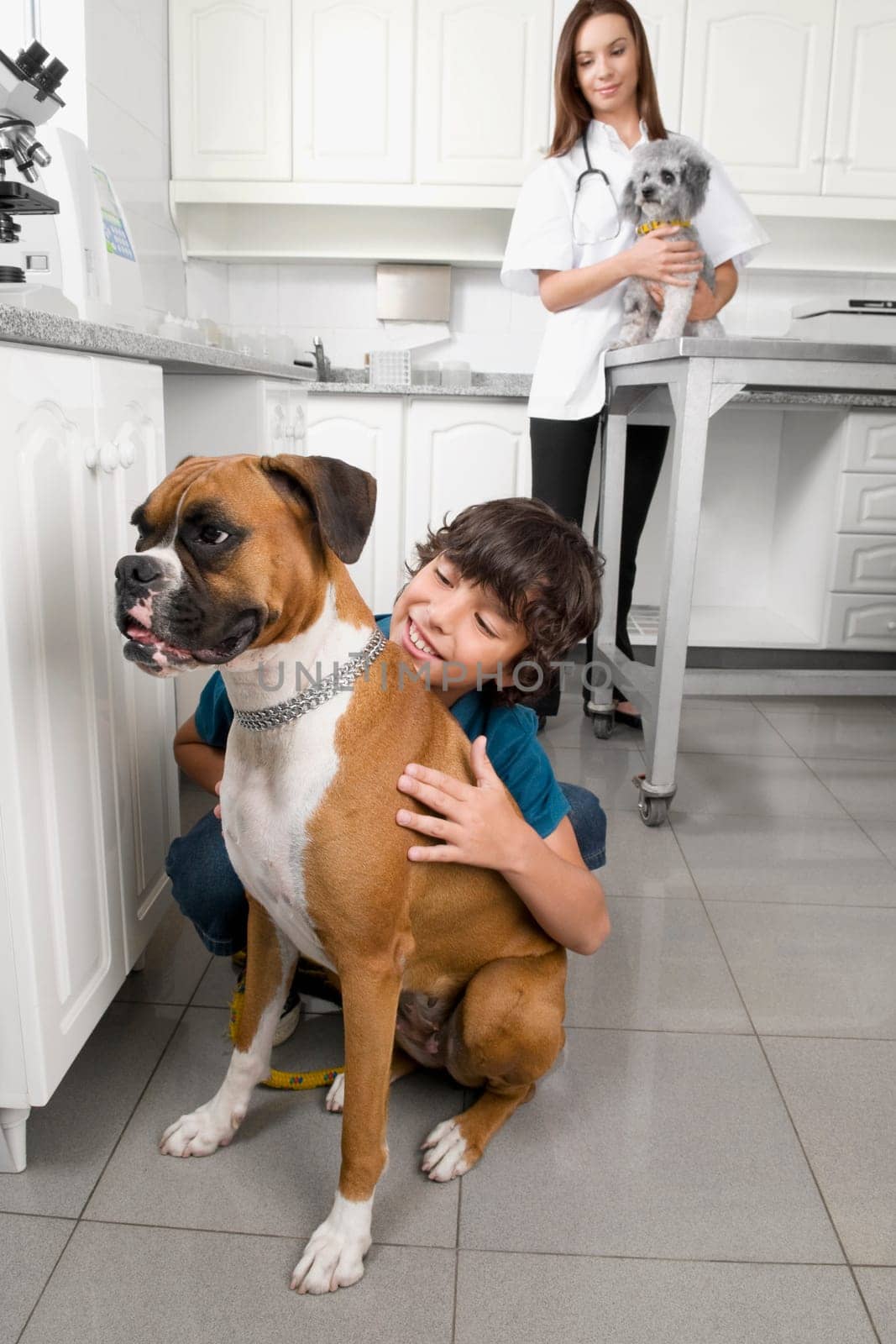 Boy hugging a dog with a vet in the background