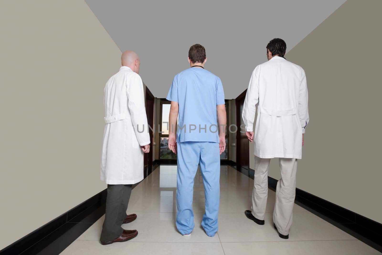 Two male doctors with a surgeon walking in a hospital corridor