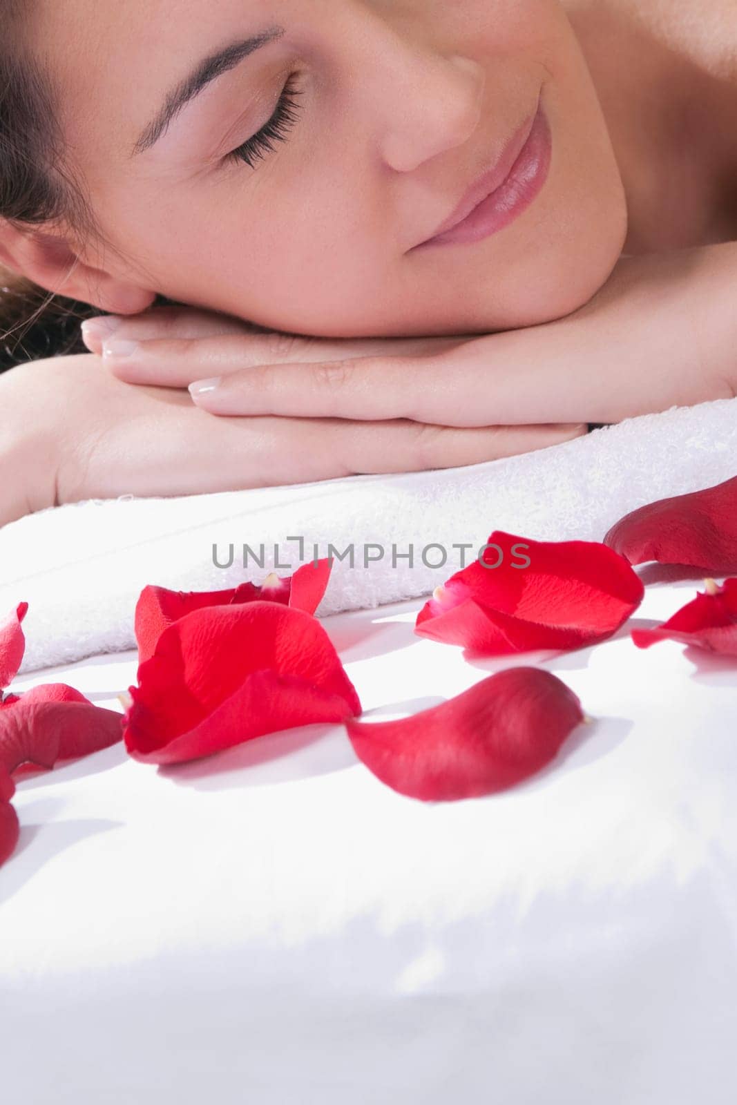 Woman lying on a massage table with rose petals in front of her