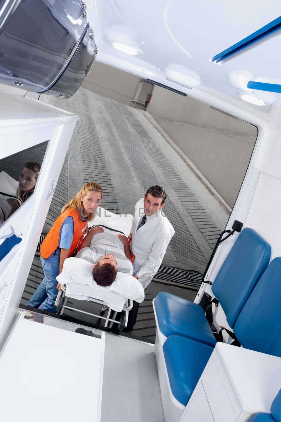 Paramedics leading a patient on a gurney into an ambulance