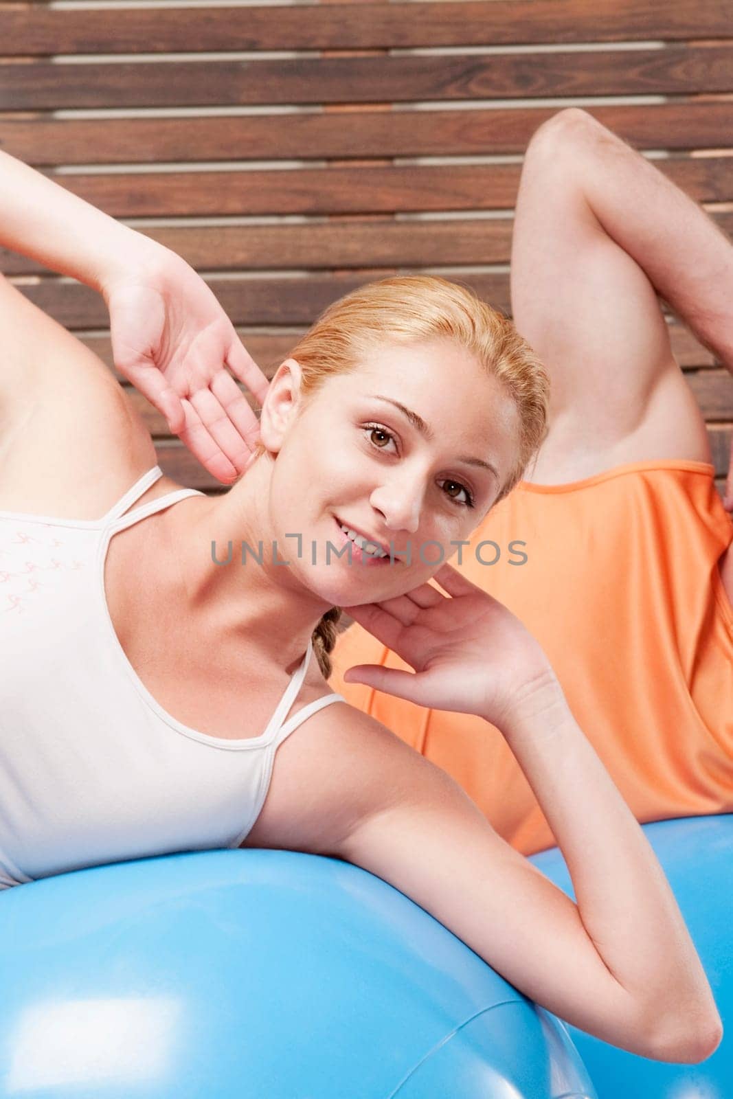 Man and a woman exercising on fitness balls in a gym