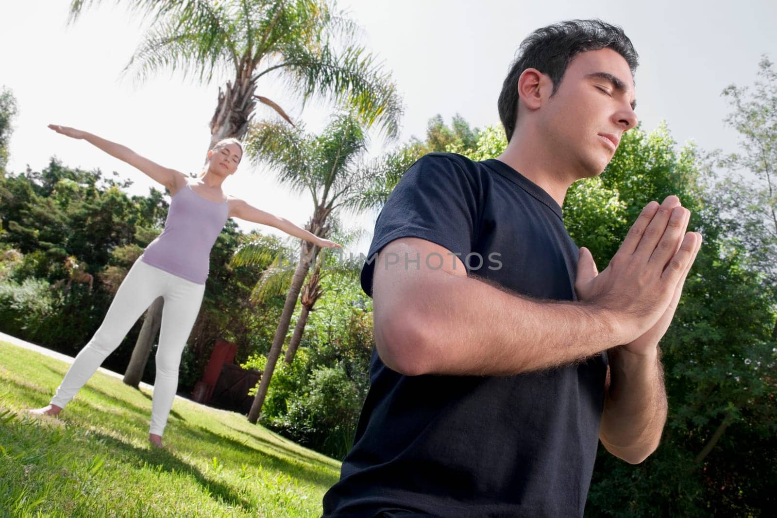 Couple practicing yoga in a park