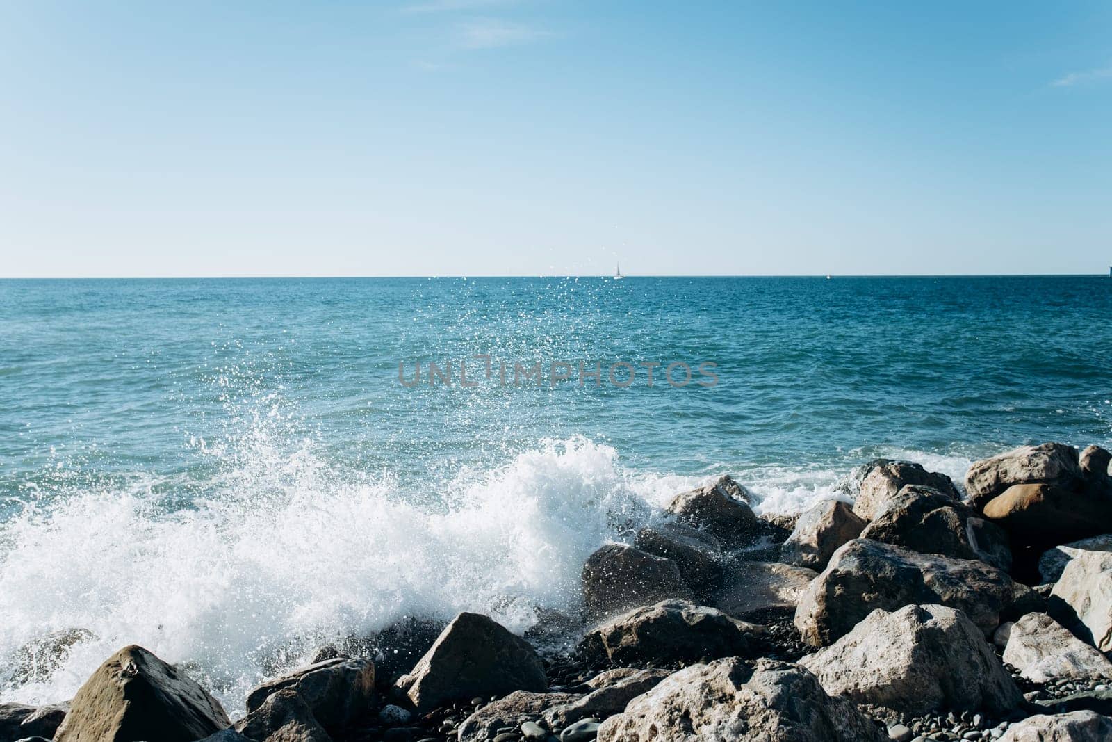 Stones on the beach. The waves of the sea beat against the rocks on the shore. Beautiful view of the sea.