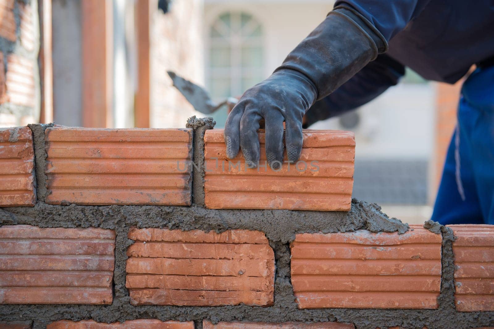 Worker building masonry house wall with bricks