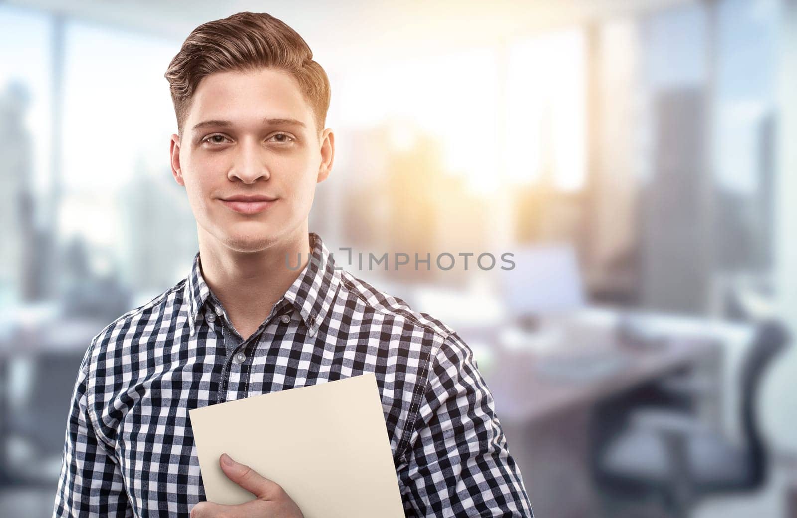 Young man holding a file in a modern office