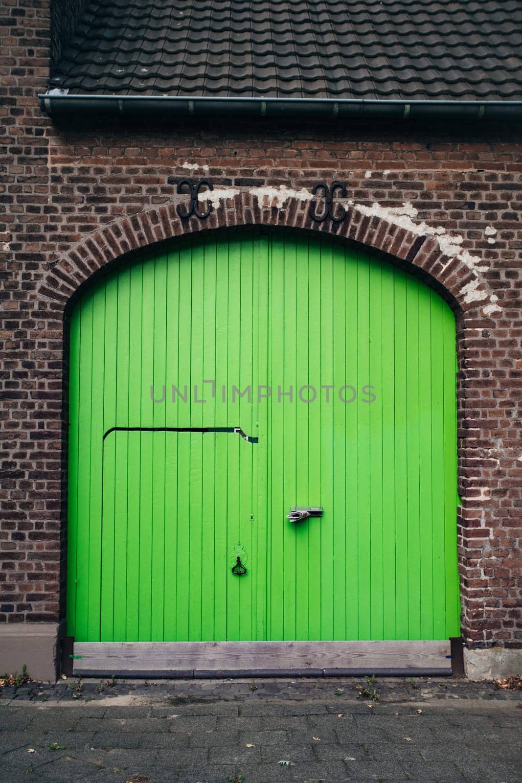 Large bright green wooden doors in an old brick building. Doors in a renovated building.