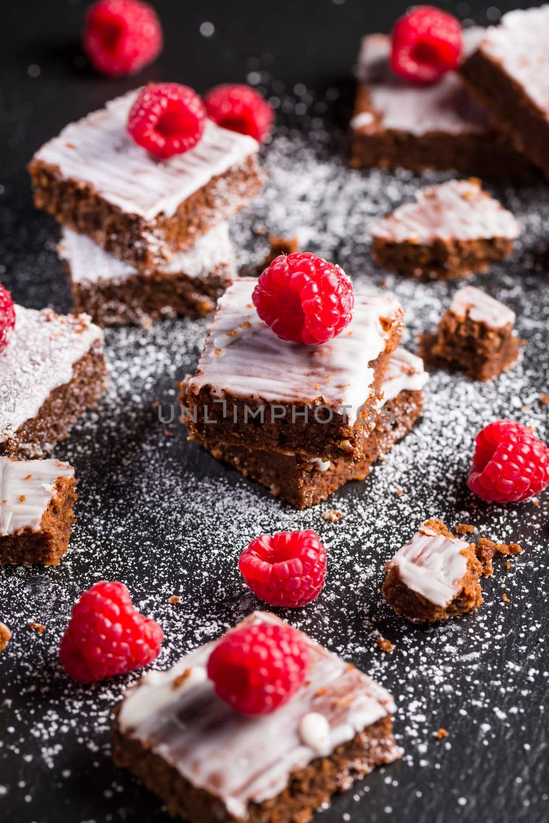 Homemade vegan chocolate brownies with nuts, lemon icing and raspberries