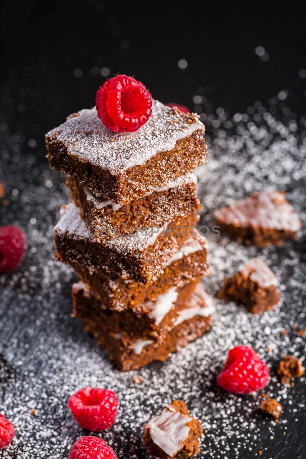 Homemade vegan chocolate brownies with nuts, lemon icing and raspberries
