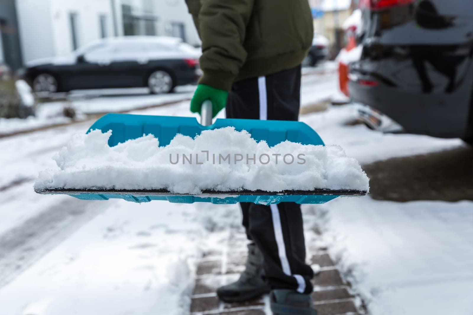 Child shoveling and removing snow in front of his house in the suburb