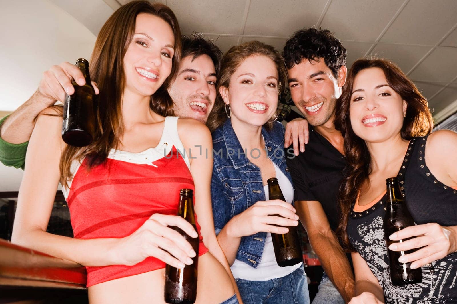 Portrait of five friends smiling at a bar counter
