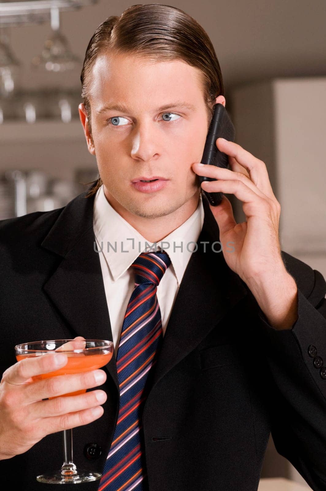 Businessman talking on a mobile phone and holding a cocktail glass