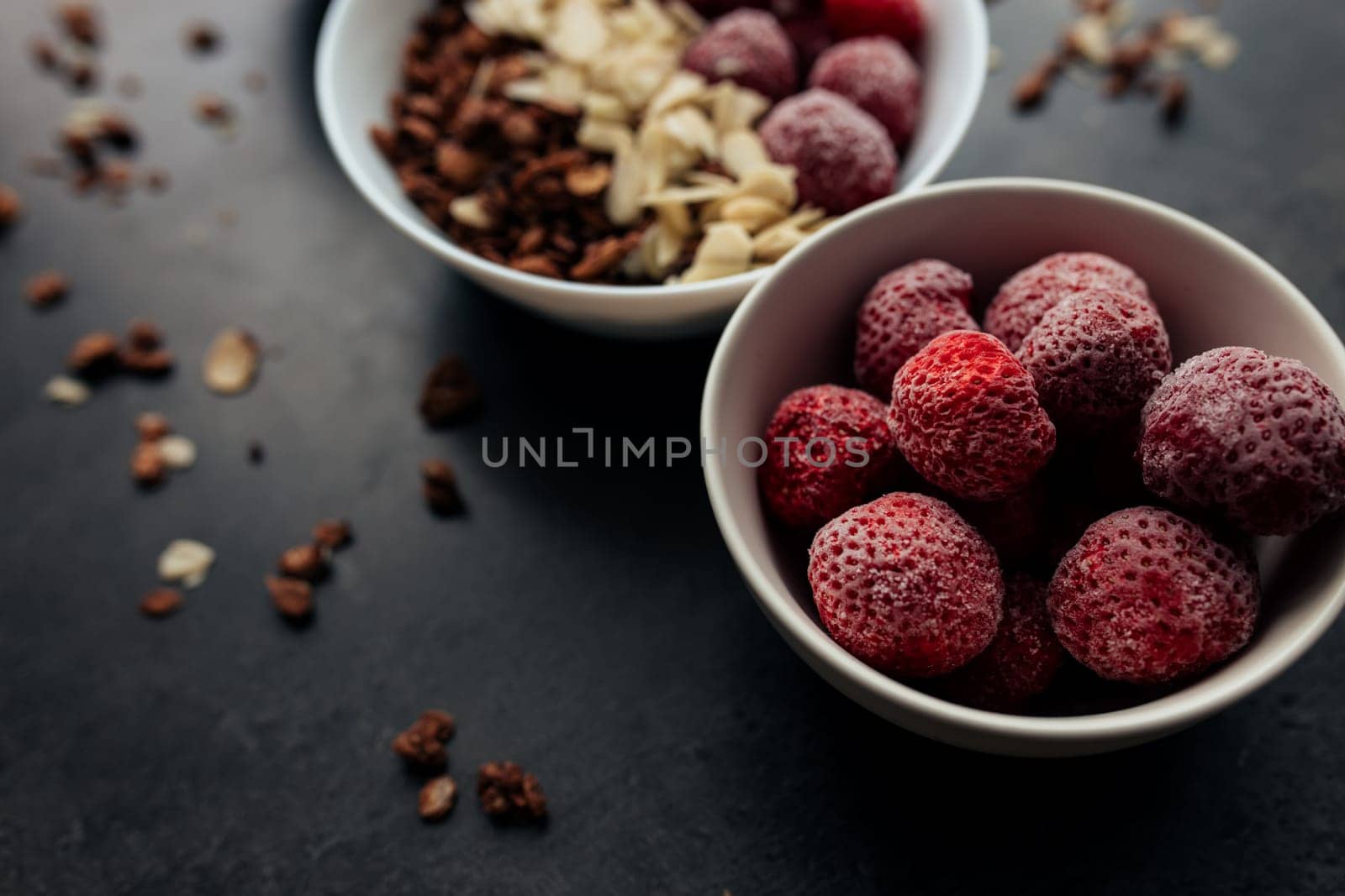 Frozen strawberry with granola, almond flakes on concrete table. High quality photo