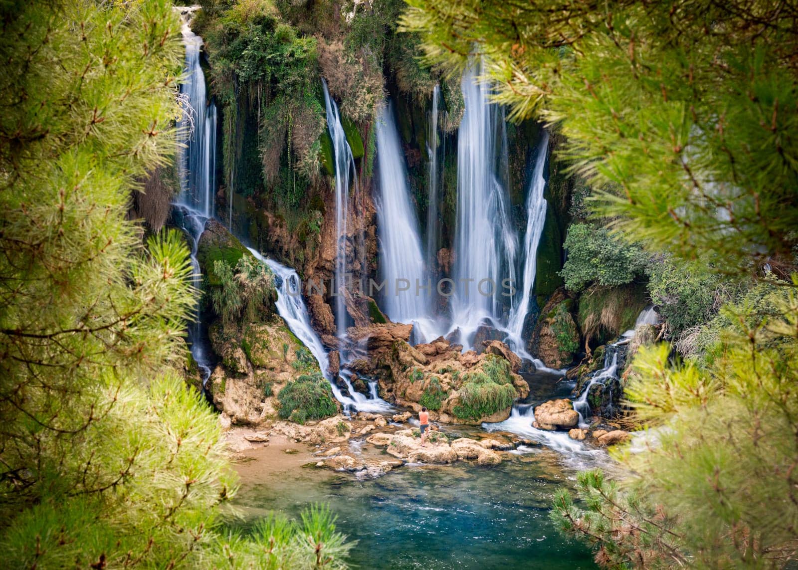Kravice Waterfalls, Bosnia and Herzegovina, Europe. Summer travel. Small figure of tourist at foot of waterfall taking pictures