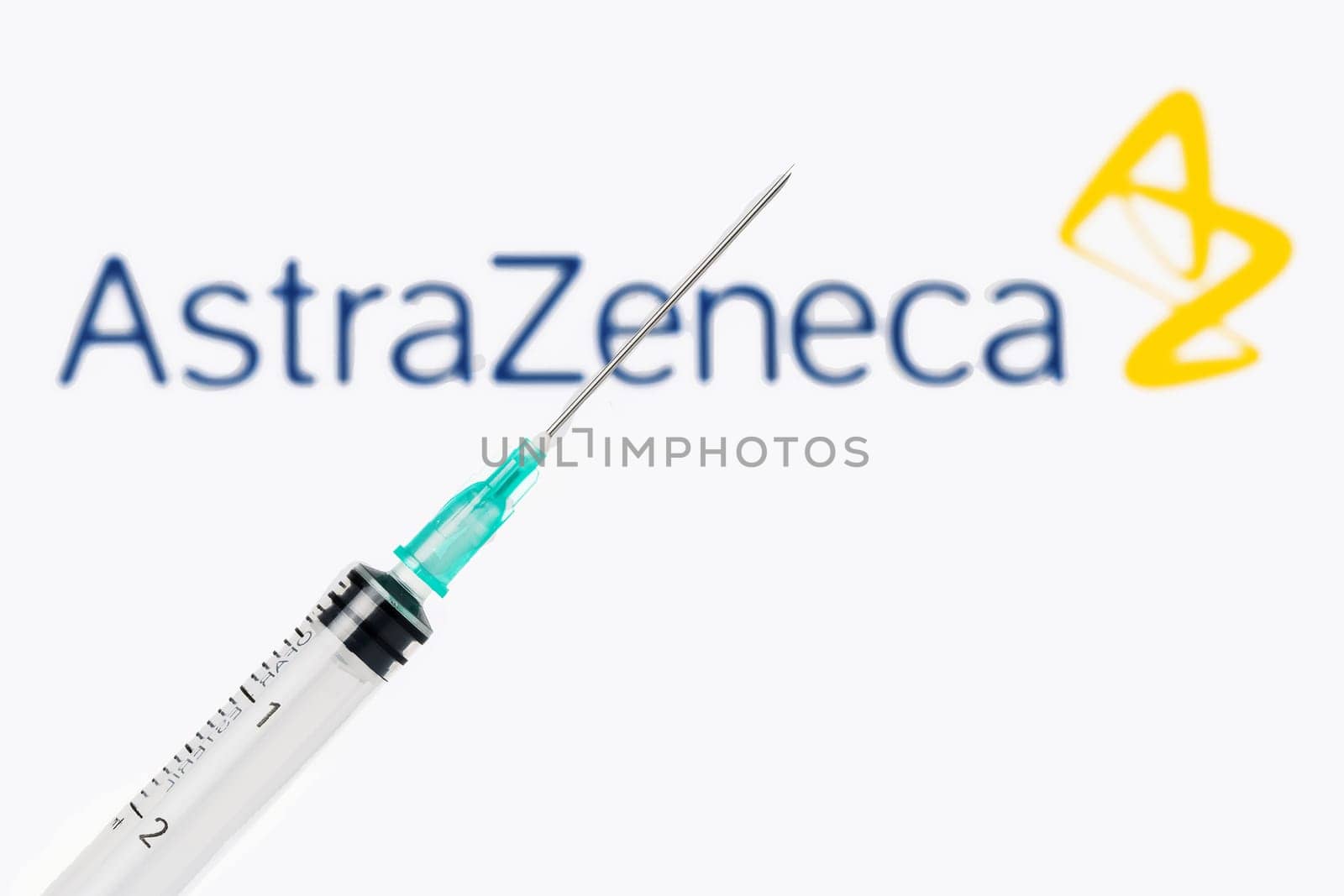 Teo, Spain  January 25, 2021: AstraZeneca Covid-19 vaccine concept. Close-up of a syringe over the AstraZeneca company logo blurred in the background.
