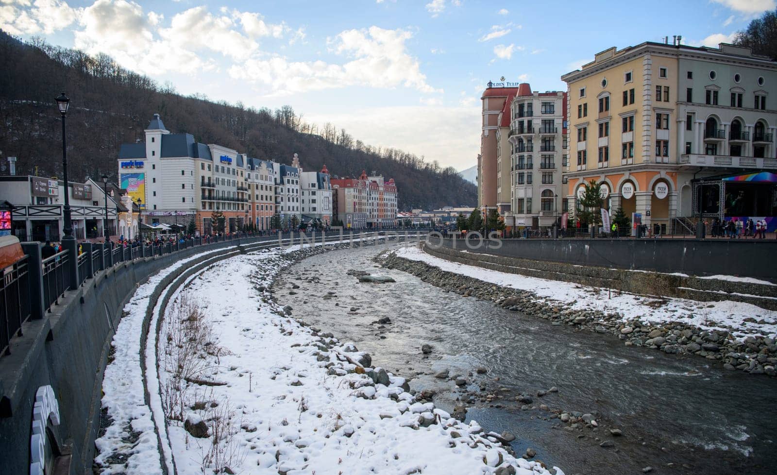 Sochi  Russia - January 02  2021: The Mzymta river in the Krasnaya Polyana resort. Tourists walk along the embankment